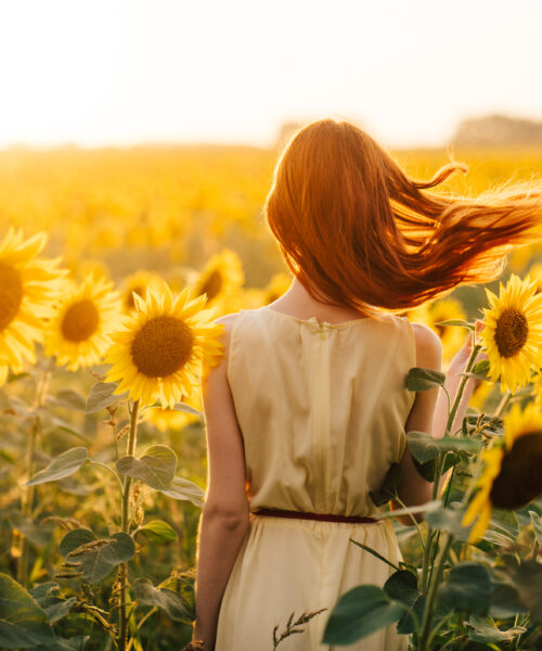 Young woman walking through a field of flowers, considering her pregnancy options.